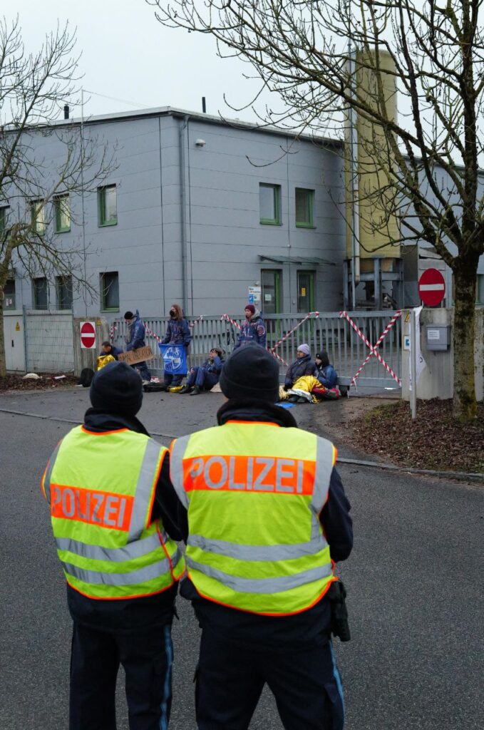 Zwei Polizisten schauen auf die Blockade der Schlachthofzufahrt.