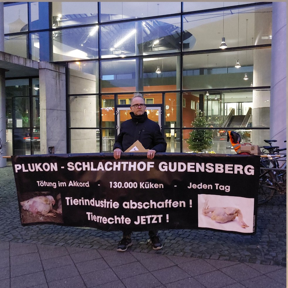 Ein Aktivist hält ein großes Banner auf dem steht "Tierindustrie abschaffen! Tierrechte Jetzt"